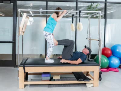 Instructor guiding a client through a Pilates Tower exercise at Denver Pilates Girl in Glendale, Colorado